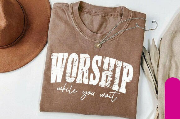 Black graphic tee from Anchored Grace Boutique featuring inspirational "Worship While You Wait" design on the front.