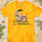 Black graphic tee with white text saying "I Read Past My Bedtime" from Anchored Grace Boutique, displayed on a hanger.