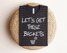 Let's Get These Buckets graphic tee by Anchored Grace Boutique, white cotton t-shirt with bold black text graphic.
