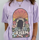 He is Risen graphic tee from Anchored Grace Boutique, featuring bold religious-themed design on a casual cotton t-shirt.