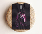 Dark graphic tee featuring Ursula design from Anchored Grace Boutique, casual fashion top with bold artistic print.