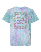 Black graphic tee from Anchored Grace Boutique featuring inspirational text "Even in the Chaos His Grace Still Finds Me" printed on the front.