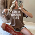 Black graphic tee from Anchored Grace Boutique featuring the phrase "Lover of Cancelled Plans" in stylish white lettering.