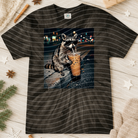 Iced coffee raccoon graphic tee from Anchored Grace Boutique, featuring a playful raccoon holding a coffee cup on a casual t-shirt.