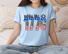 Red graphic tee featuring "Party Like It's 1776" slogan from Anchored Grace Boutique, casual style, with patriotic design.