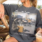 Black graphic tee from Anchored Grace Boutique with "I Live Here Now" print, casual style, and comfortable fit.