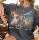 Black graphic tee from Anchored Grace Boutique featuring the phrase "Just Vibing Through Unprecedented Times" in bold white lettering.