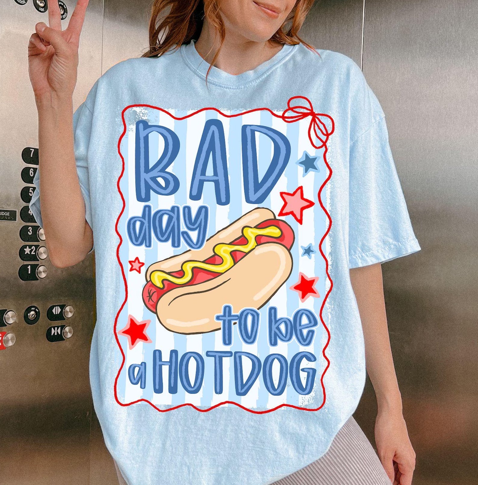 Black graphic tee by Anchored Grace Boutique featuring humorous "Bad Day to Be a Hotdog" design on soft cotton fabric.