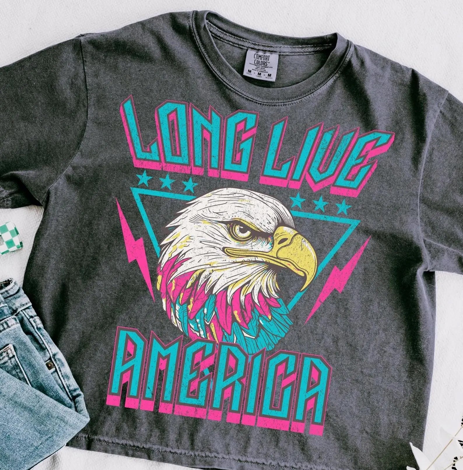 Long Live America graphic tee by Anchored Grace Boutique, featuring patriotic design and casual fit on white fabric.