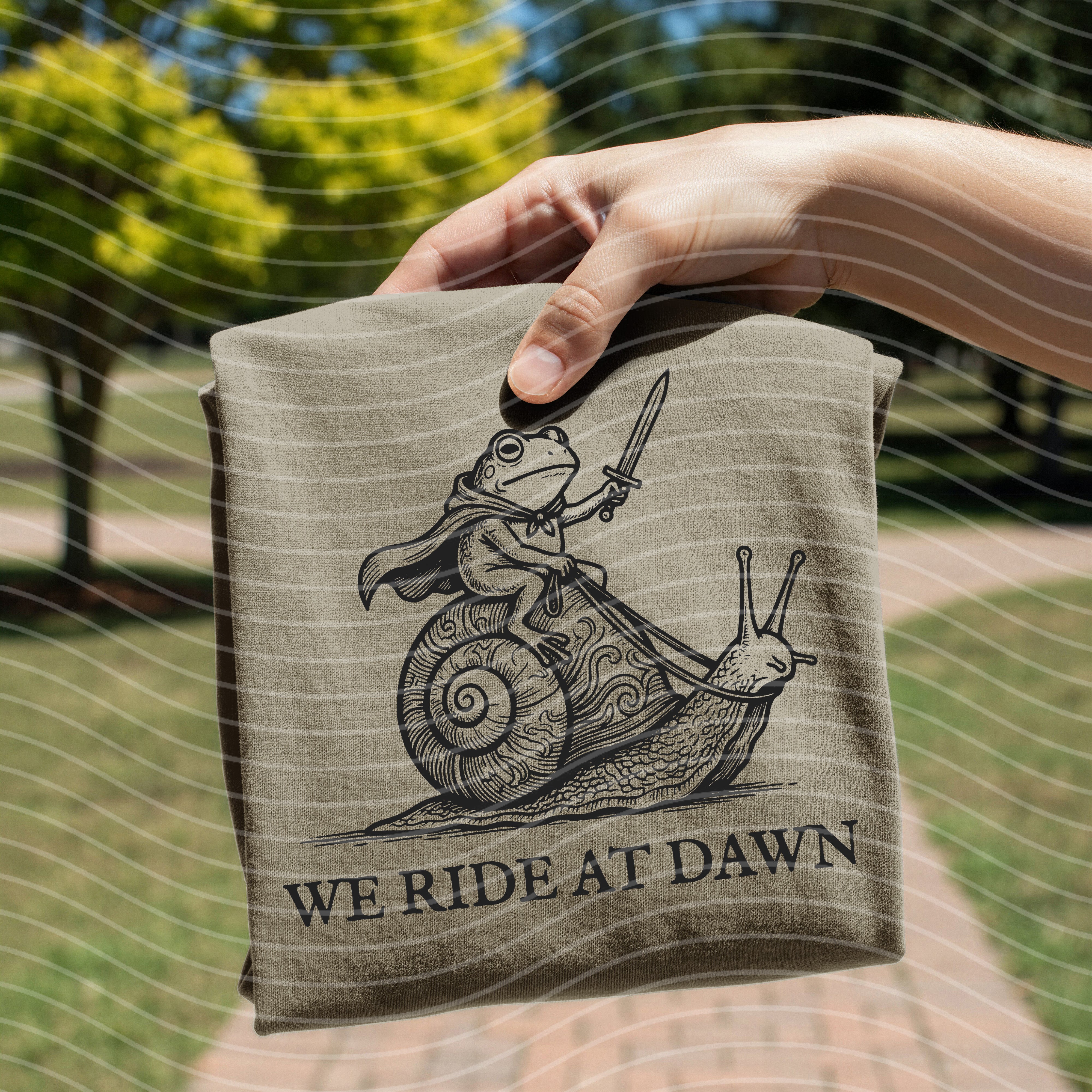 Black graphic tee from Anchored Grace Boutique featuring "We Ride at Dawn" slogan and dawn-themed design.
