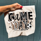 Black Game Day Soccer graphic tee from Anchored Grace Boutique featuring a sporty soccer design and casual fit.
