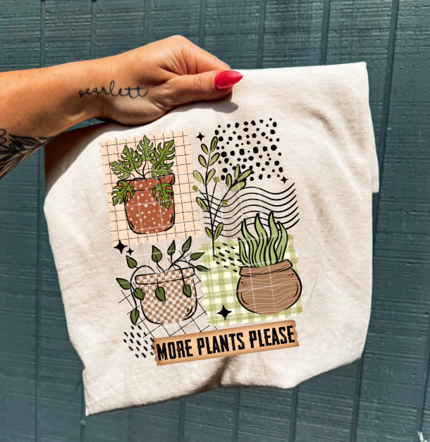 Anchored Grace Boutique graphic tee featuring the "More Plants Please" design, casual cotton shirt with green plant illustrations.