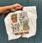 Anchored Grace Boutique graphic tee featuring the "More Plants Please" design, casual cotton shirt with green plant illustrations.