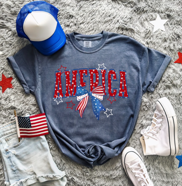 American flag bow graphic tee by Anchored Grace Boutique, featuring a colorful bow and flag design on a casual cotton t-shirt.