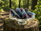 Purple, blue, and green banded fluorite wand with a polished surface, showcasing vibrant colors and natural crystal patterns.