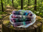 Purple, blue, and green banded fluorite wand with smooth polished surface, showcasing vibrant mineral colors and natural striations.