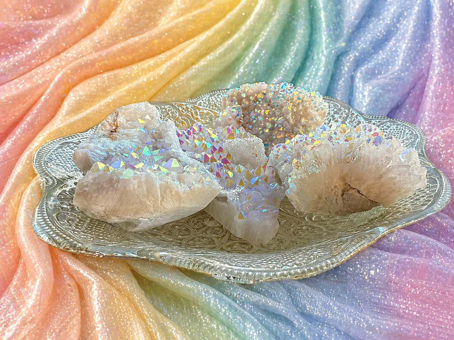 Angel Aura Quartz clusters featuring shimmering, iridescent crystal formations with vibrant rainbow hues, displayed on a neutral background.