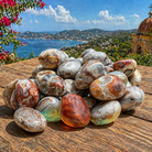 Smooth Mexican Laguna Lace Agate tumble stones with intricate banding and warm earth tones, showcasing natural gemstone beauty.