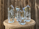 Polished clear quartz crystal tower from Practical Magic Store with natural crackle details and smooth, shiny surface.