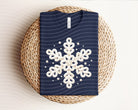White graphic tee by Anchored Grace Boutique featuring a snowflake design on the front, casual and stylish for everyday wear.