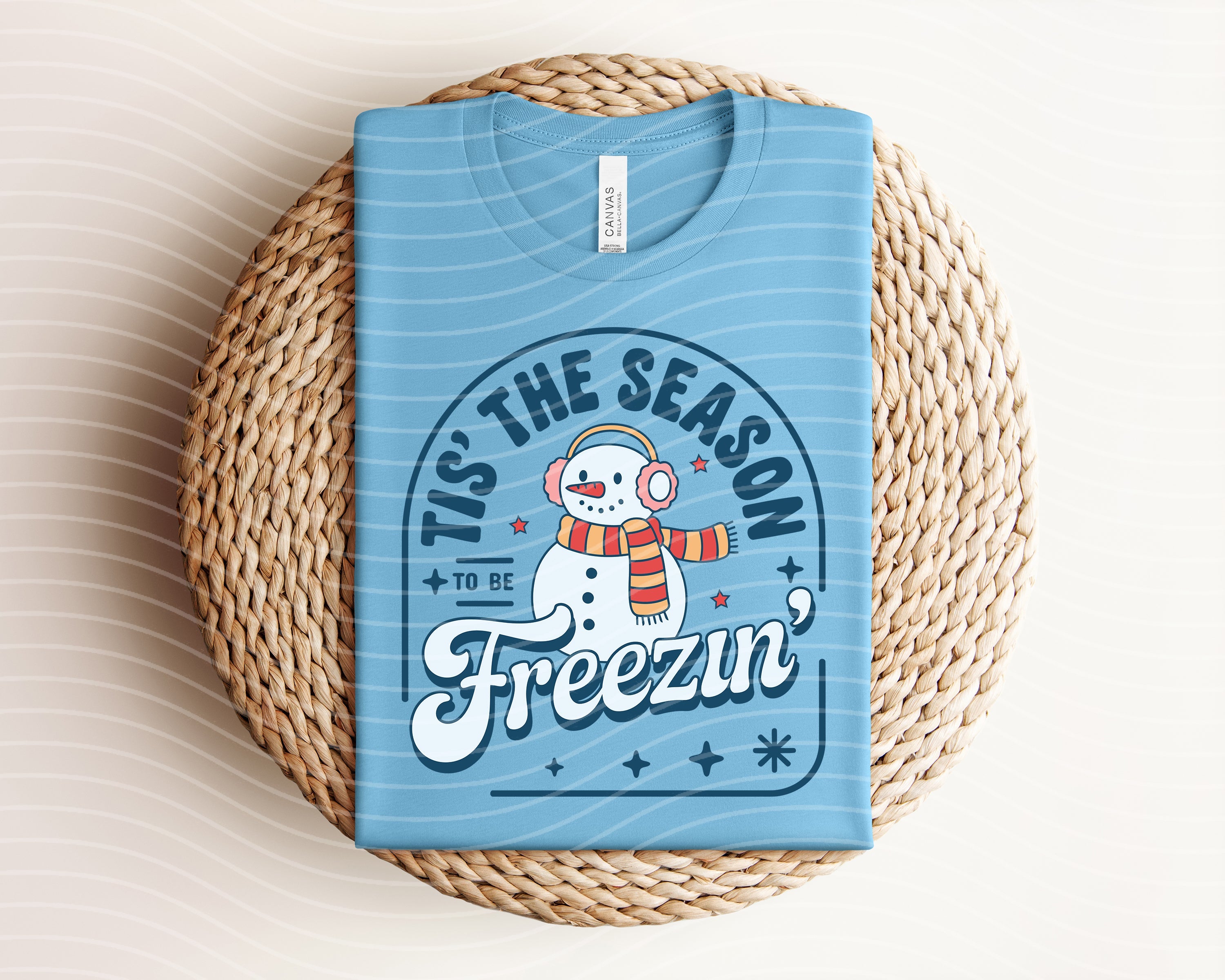 Graphic tee featuring festive "Tis the Season to Be Freezin" design from Anchored Grace Boutique, with holiday-themed winter graphics.