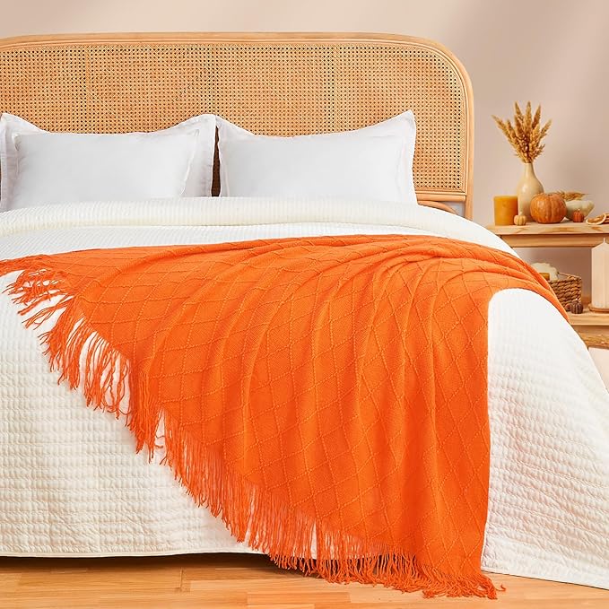 CozyNest Decor burnt orange fall throw blanket on a couch, soft knitted textile, perfect for autumn home decor and cozy living spaces.