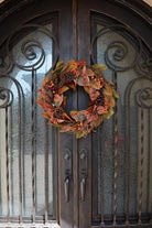 CozyNest Decor 24-inch artificial fall magnolia leaf wreath with orange pinecones and berries, perfect for door or wall decoration.