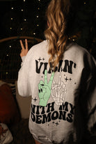 Vibin' with My Demons graphic sweatshirt by Shop Karma Tees featuring dark-themed demon illustrations and bold text design.