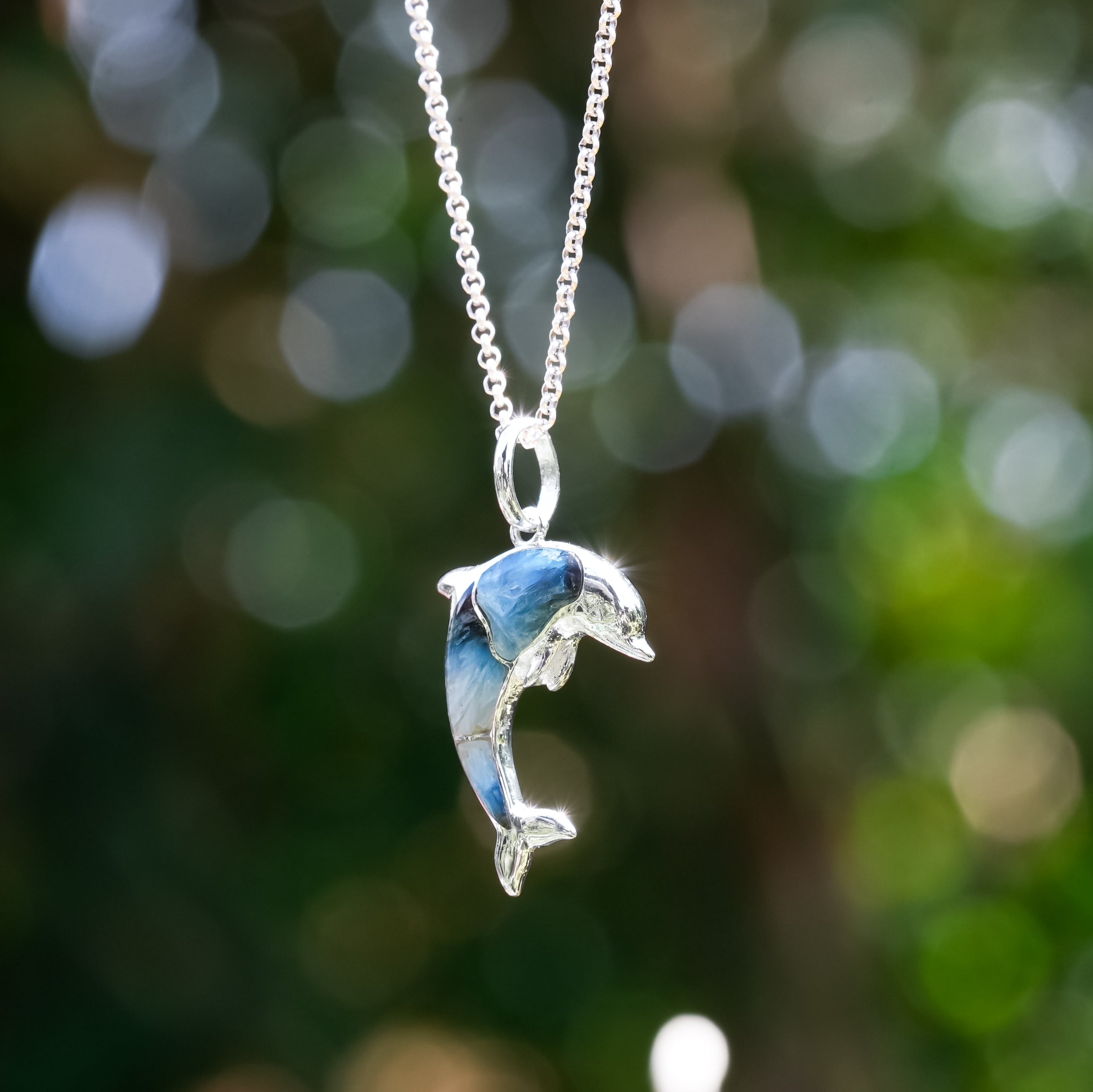 Sterling silver dolphin pendant with colorful gemstone inlay from Starborn Creations, showcasing detailed marine-inspired jewelry design.