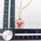 Dried flowers in an irregular round pendant necklace, featuring natural floral designs on a jewelry piece for nature lovers.