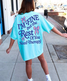 White cotton t-shirt featuring the phrase "I’m Fine, But Yall Need Therapy" in bold black text, casual fit, Shop Karma Tees brand.