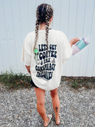 Black graphic tee featuring coffee cups and conspiracy theory illustrations, stylishly displayed on a hanger.