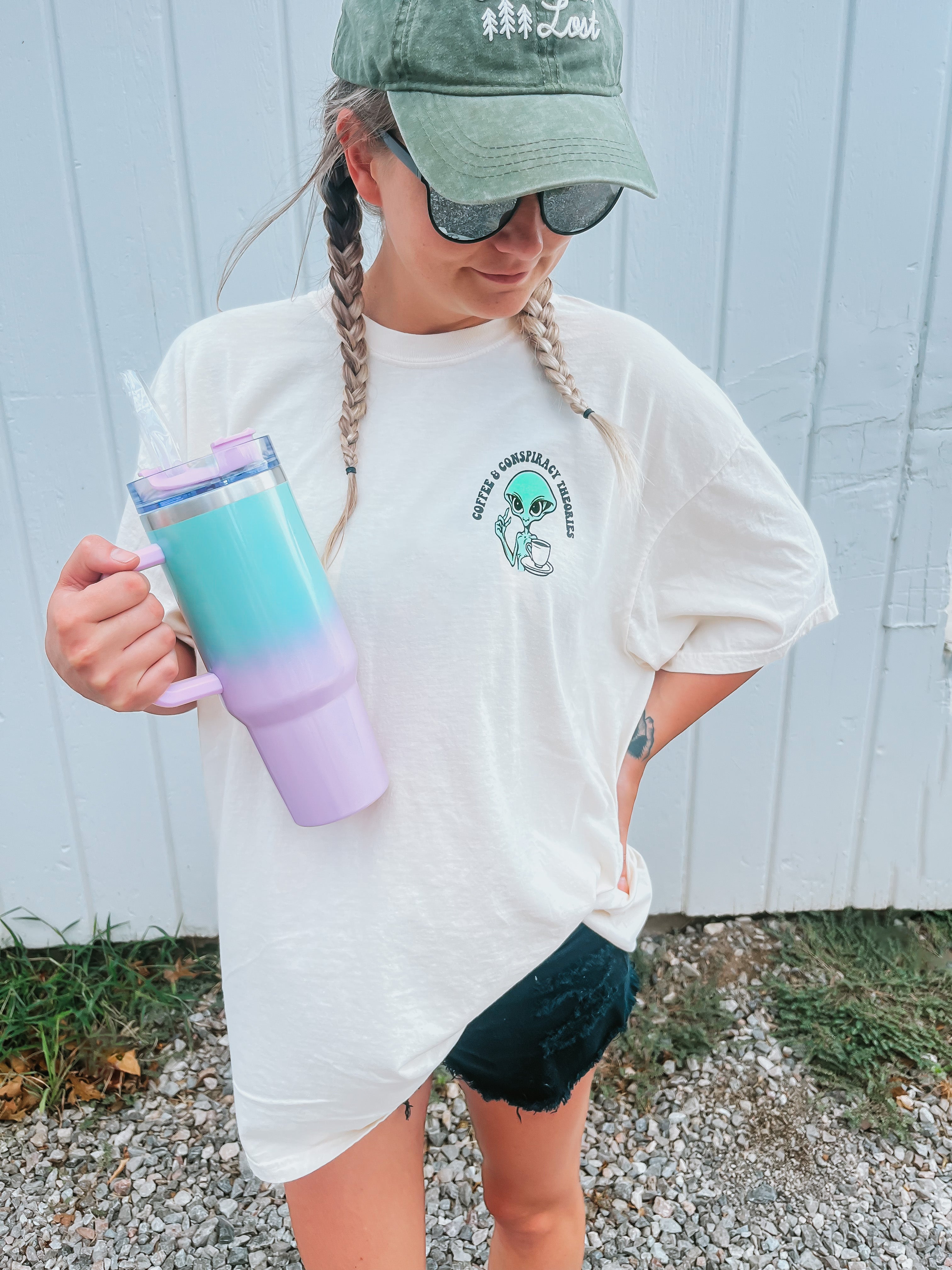 Black graphic t-shirt featuring coffee cups and conspiracy theory illustrations, stylish design from Shop Karma Tees.