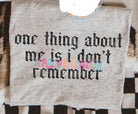 Black graphic tee from Anchored Grace Boutique featuring the phrase "One Thing About Me Is I Don't Remember" in bold white text.