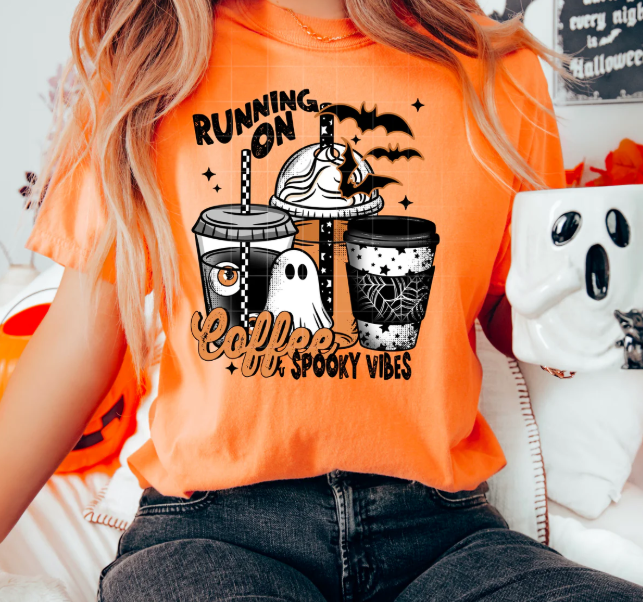 Black graphic tee from Anchored Grace Boutique featuring "Running on Coffee and Spooky Vibes" design, with spooky-themed text and illustrations.