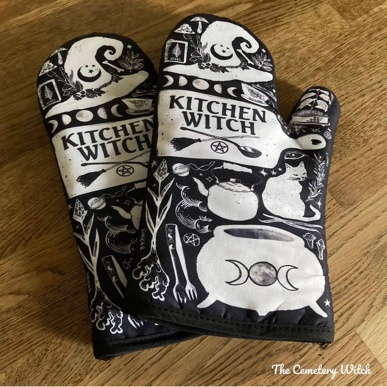 Set of 2 Kitchen Witch oven mitts and pot holders from The Bullish Store, hanging oven gloves with colorful witch design.