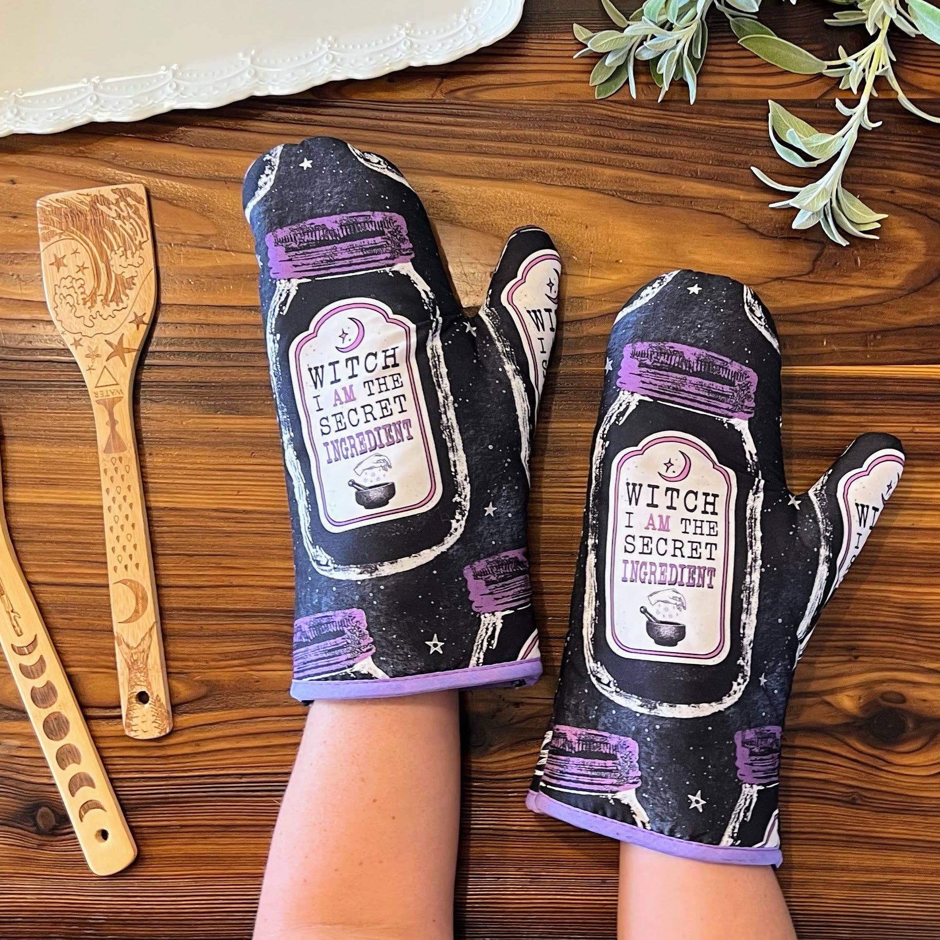 Set of 2 witch-themed oven mitts and pot holders from The Bullish Store, hanging and featuring the phrase "I AM The Secret Ingredient."