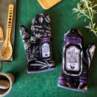 Set of 2 witch-themed oven mitts and pot holders from The Bullish Store, hanging and featuring "I AM The Secret Ingredient" design.