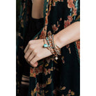 Stack of nine bohemian-inspired pastel beaded and studded bracelets, layered with colorful beads and silver studs.