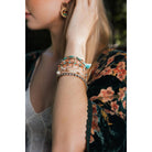 Stack of nine pastel beaded and studded bohemian-inspired bracelets with layered design, featuring colorful beads and metal studs.