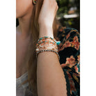 Stack of nine bohemian-inspired pastel beaded and studded bracelets with metal accents, layered for a stylish jewelry look.