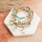 Stack of nine pastel beaded and studded bohemian-inspired bracelets with layered design, featuring colorful beads and metal studs.