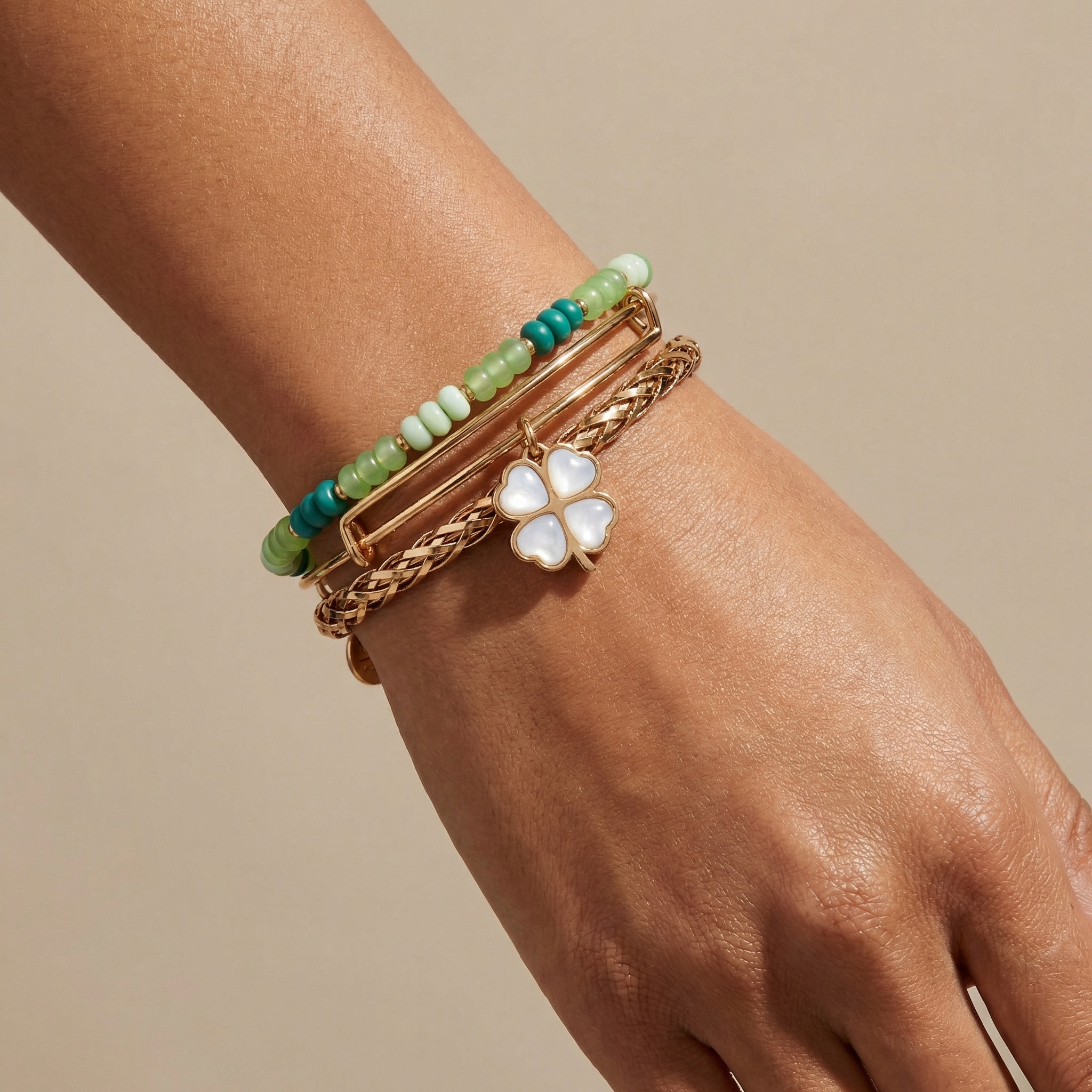 Set of three gold ALEX AND ANI lucky four-leaf clover bracelets, stylish jewelry bangles with engraved clover charms.