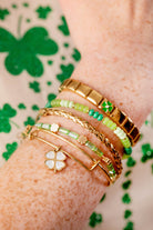 Set of three gold ALEX AND ANI Lucky Four-Leaf Clover bangles, stacked bracelets with four-leaf clover charms.