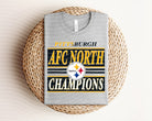 Black AFC North Champions Steelers graphic tee featuring team logo and bold text, casual apparel from Anchored Grace Boutique.