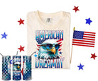 American Dreamin graphic tee by Anchored Grace Boutique featuring bold text and vibrant design on a casual cotton shirt.