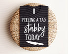 Feeling a Tad Bit Stabby Today graphic tee by Anchored Grace Boutique, featuring bold text and casual fit on a white T-shirt.