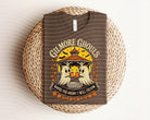 Green Gilmore Ghouls graphic tee from Anchored Grace Boutique featuring a spooky design on a casual short-sleeve shirt.