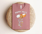 Happy Pills graphic tee by Anchored Grace Boutique featuring colorful pill and happy face designs on a casual cotton t-shirt.