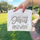 Black graphic tee with white text reading "I don't know your questions but I know Jesus is the answer," from Anchored Grace Boutique.
